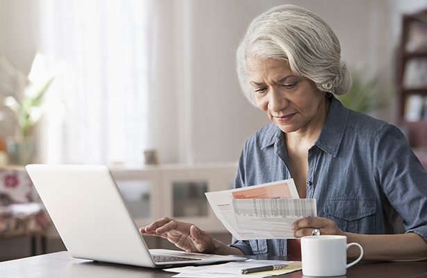 Older Black woman paying bills on laptop