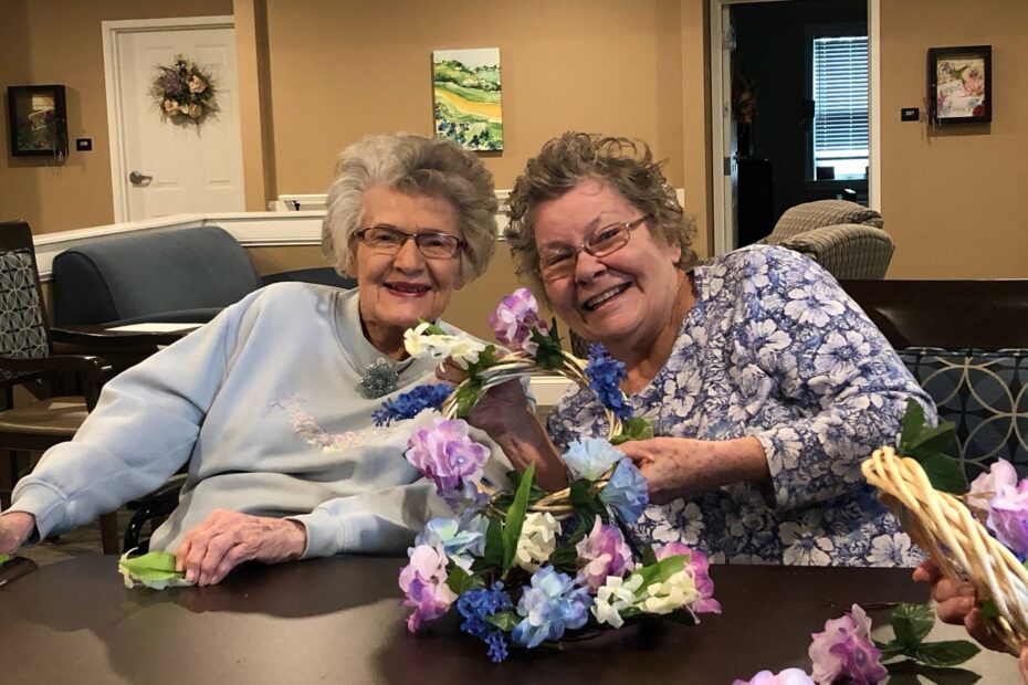 Two senior ladies smiling with flowers